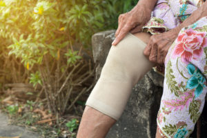 Woman adjusts knee brace on right leg 