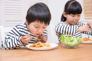 Children eating pasta with moringa marinara sauce