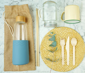 Zero-waste, plastic-free tableware flatlay overhead with bamboo and natural fibers to replace single use plastic products.