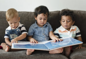 Three kids reading a book on the sofa